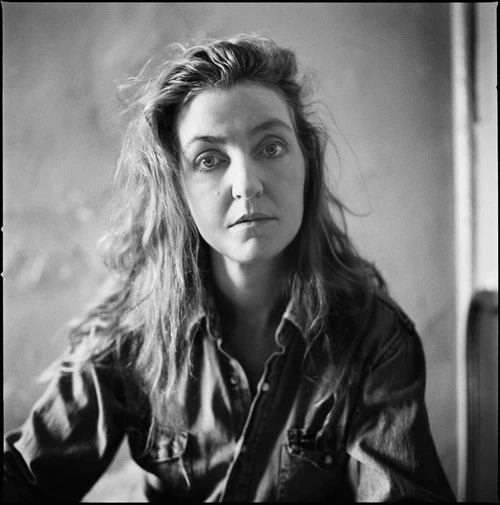 Black-and-white portrait of writer and activist Rebecca Solnit looking directly at the camera in an interior setting.