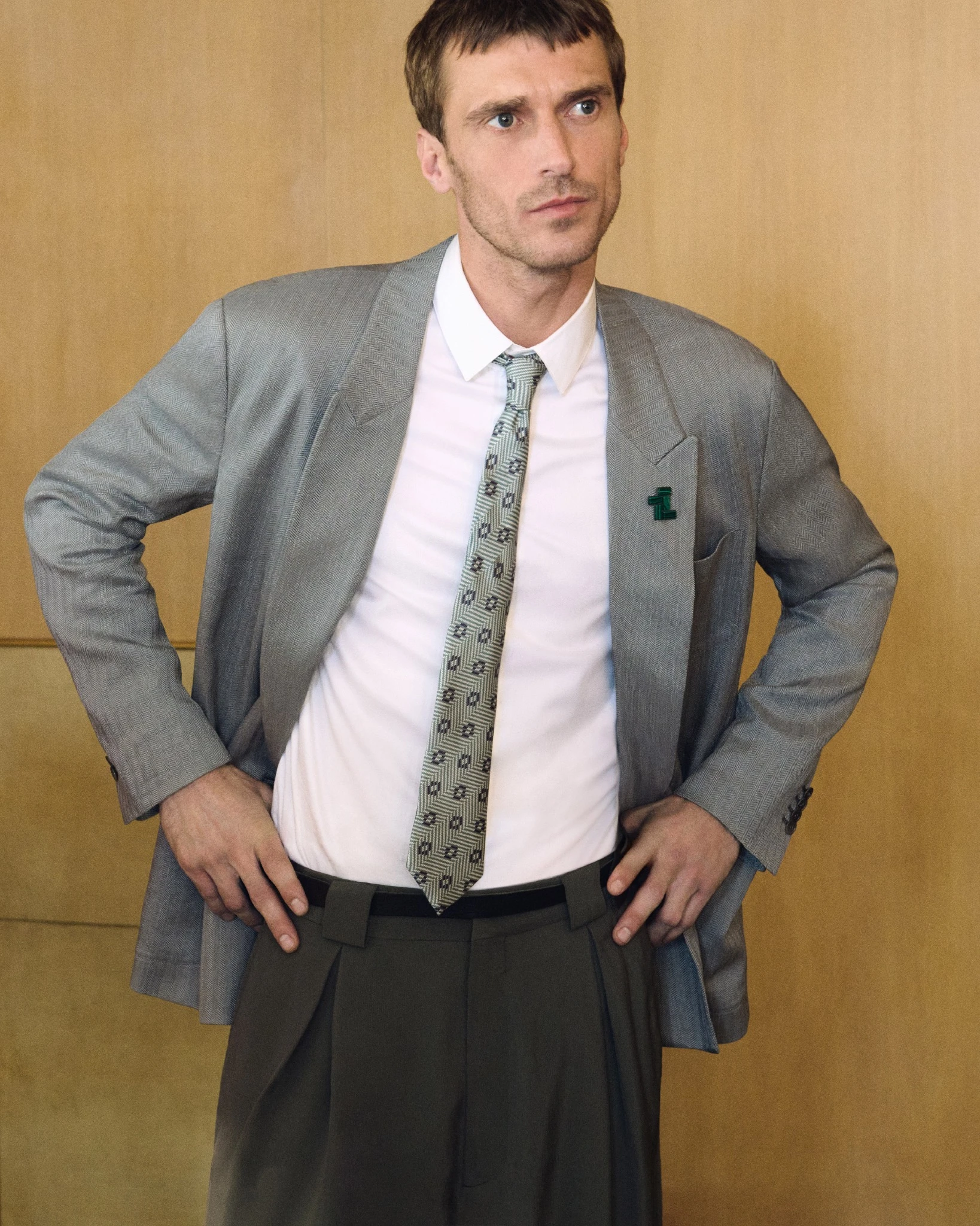 Clement Chabernaud photographed for the Giorgio Armani Spring Summer 2026 campaign, wearing a relaxed tailored suit with a patterned tie against a warm interior backdrop.