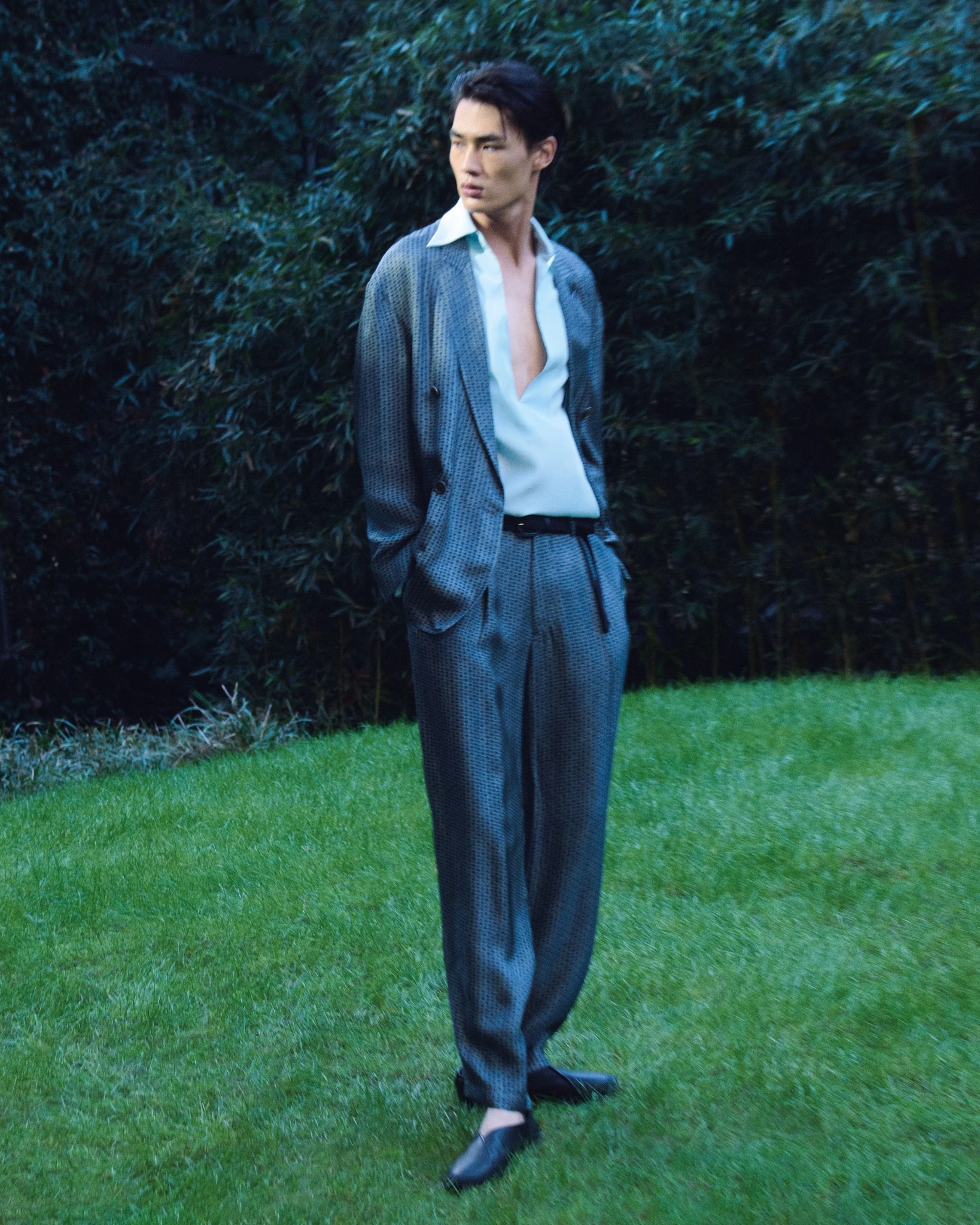 Zhaoyi Fan photographed for the Giorgio Armani Spring Summer 2026 campaign, wearing relaxed patterned tailoring and an open shirt in the garden of the designer’s Milan residence