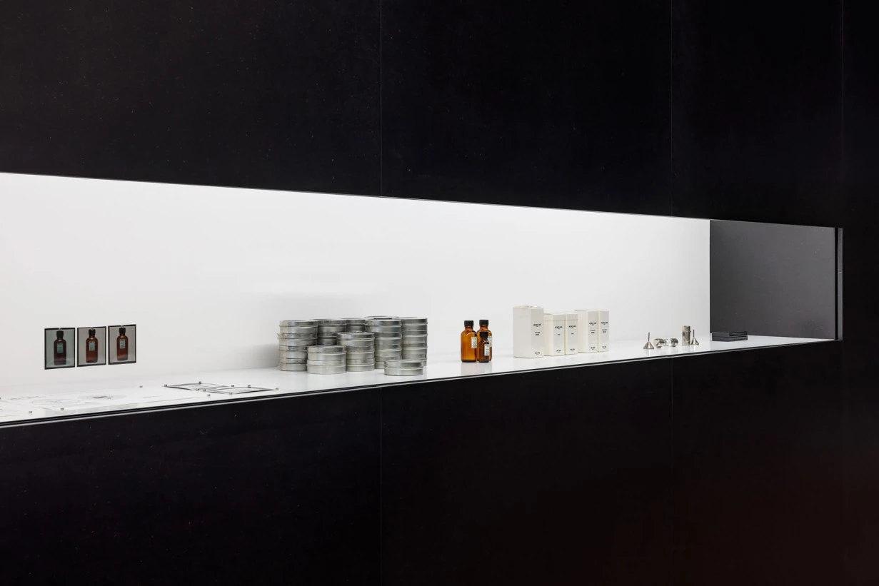 Exhibition view of Helmut Lang SEANCE DE TRAVAIL 1986–2005 at MAK Vienna showing minimalist display of Helmut Lang Parfums materials and objects