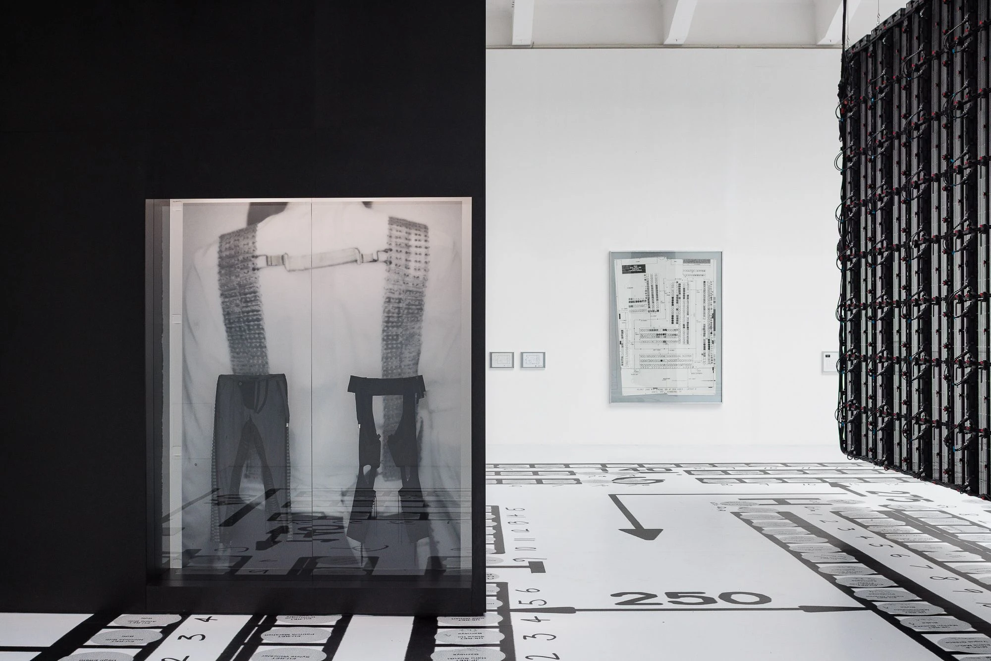 Exhibition view of Helmut Lang SANCE DE TRAVAIL 1986–2005 at MAK Vienna featuring large scale installation, graphic floor elements, and archival imagery