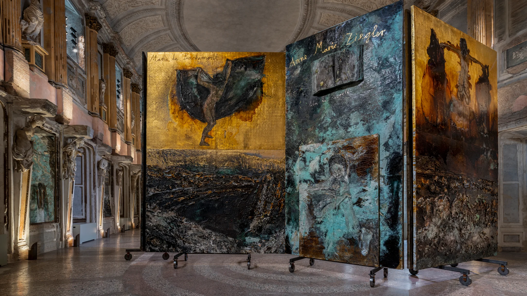 Installation view of Anselm Kiefer’s “The Women Alchemists” at Palazzo Reale, Sala delle Cariatidi, Milan, featuring large-scale textured panels with alchemical and figurative imagery.