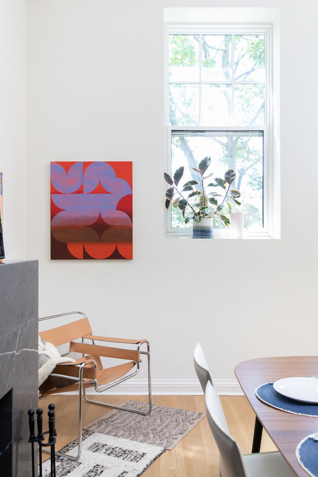 Marcel Breuer Wassily chair beside abstract red painting and rubber plant in bright modern living room