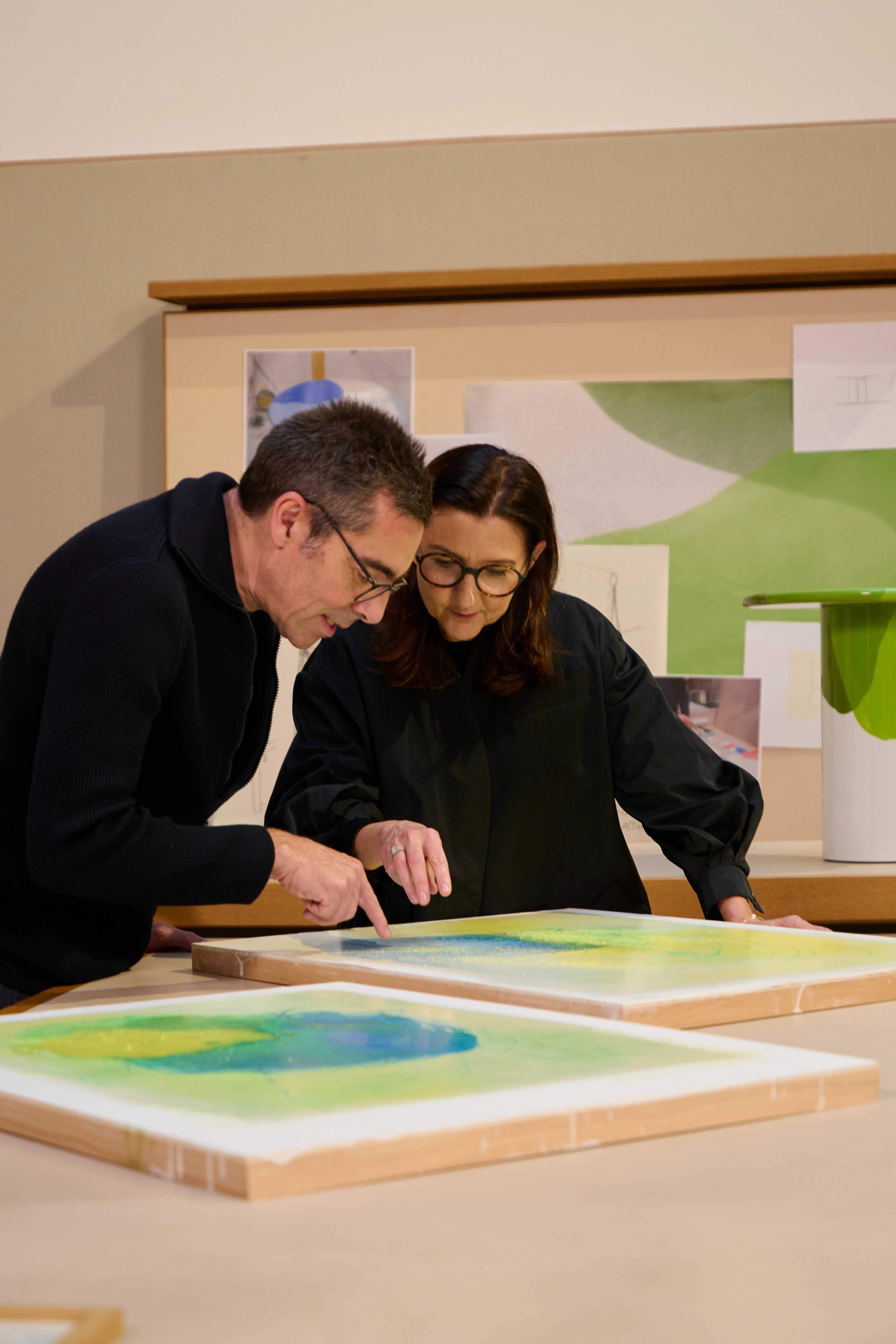 Patrick Jouin and Sophie Delafontaine examining colorful artwork prints in a design studio