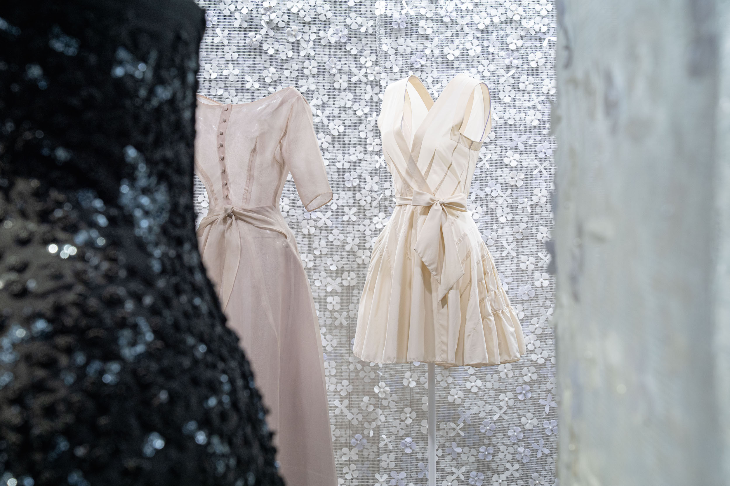Azzedine Alaia and Christian Dior haute couture dresses displayed on mannequins in exhibition installation