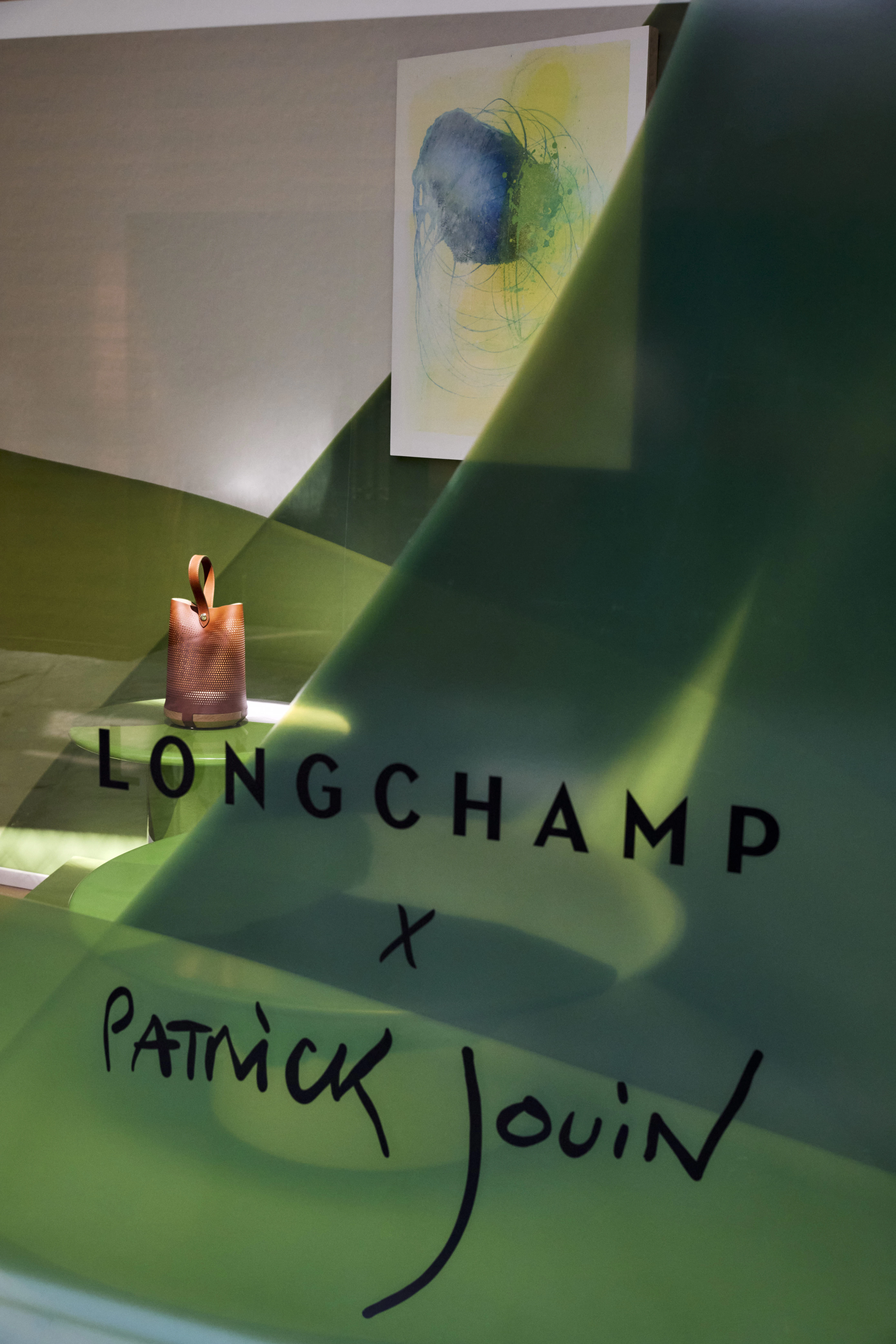 Longchamp x Patrick Jouin collaboration window display with tan leather bucket bag and green sculptural installation
