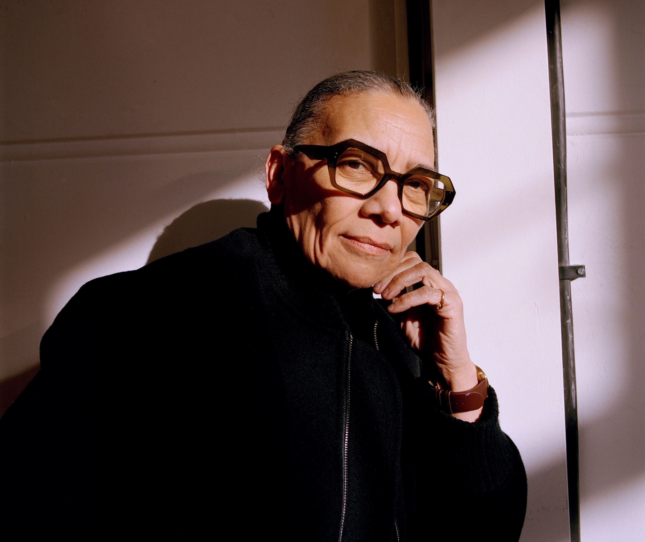 Lubaina Himid, Turner Prize-winning British artist, posing thoughtfully in black jacket with bold geometric glasses
