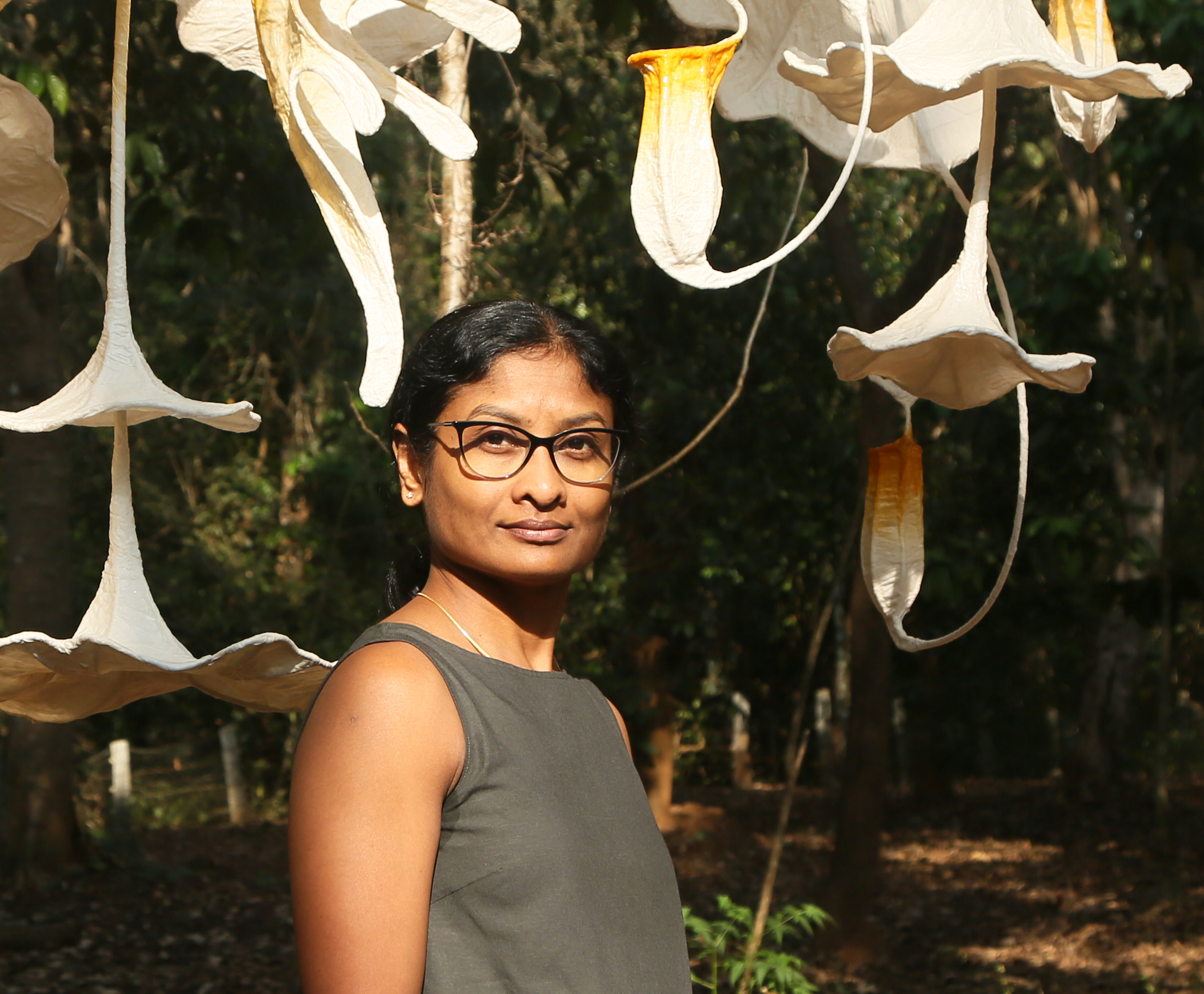 Indian sculptor Ranjani Shettar standing among large white hanging flower sculptures outdoors