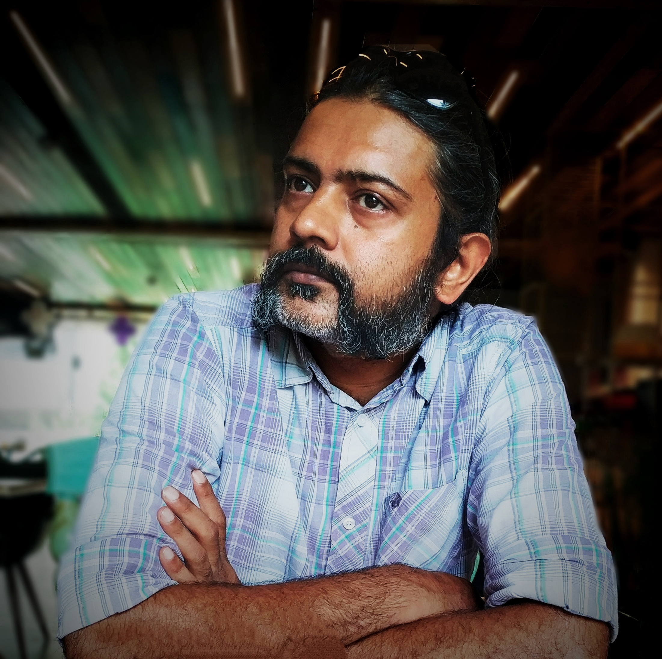 Asim Waqif, Indian contemporary artist, seated with arms crossed in studio