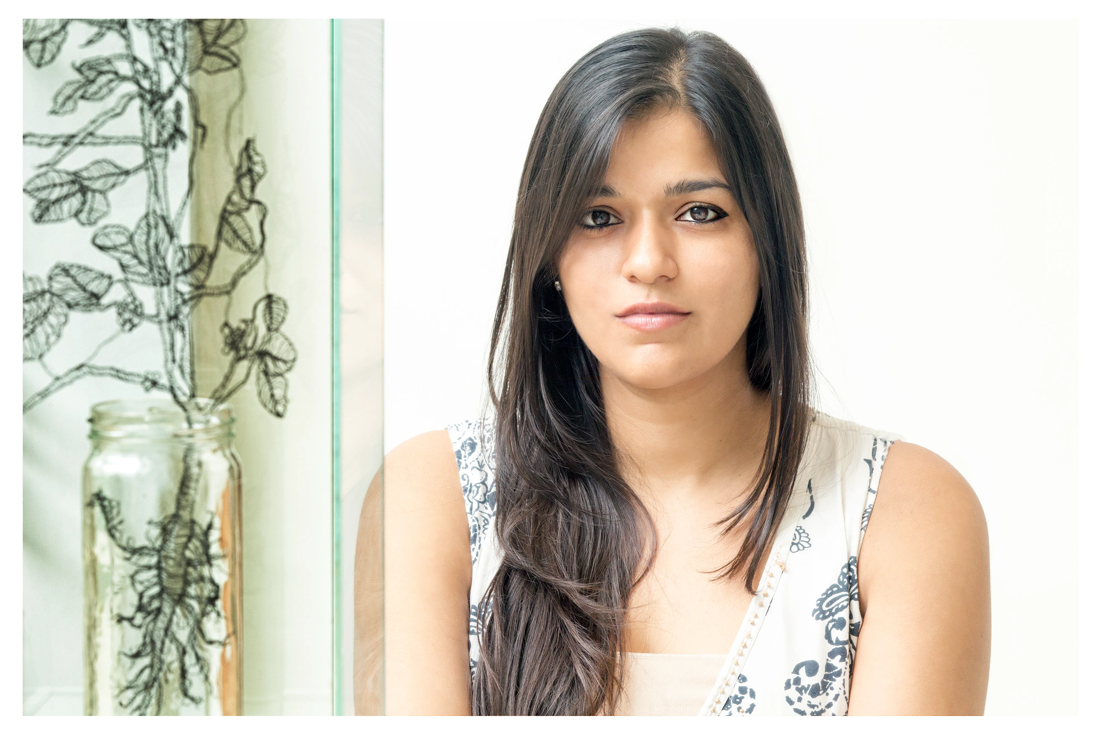 Sumakshi Singh, contemporary visual artist, seated near decorative glass installation