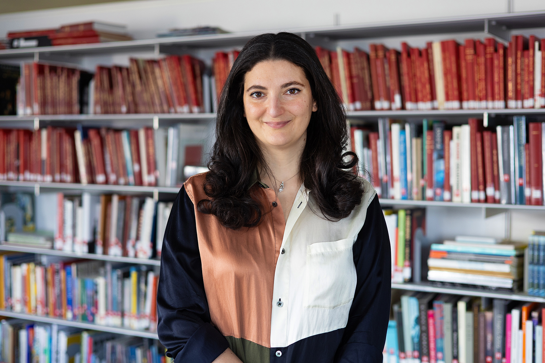 Bana Kattan smiling in a library, photo by Dahlia Dandashi for National Pavilion UAE Venice Biennale